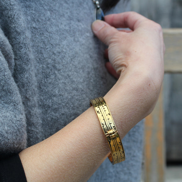 Brass Pocket dial bangle worn on a models wrist outside Shakespeare's Birthplace
