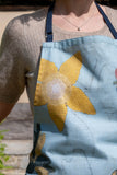 Detail of the blue apron, featuring the yellow flower pattern.