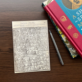 Postcard on a dark brown table, placed next to a pen and books