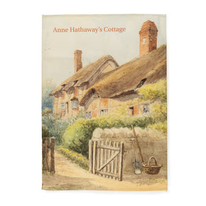 Souvenir tea towel featuring an atmospheric pastel watercolour painting of Anne Hathaway's Cottage, with the garden gate open and a basket and gardening tools positioned next to the fence.