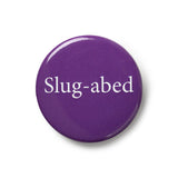 Purple button badge with traditional pin fastening. White text says 'Slug-abed'.