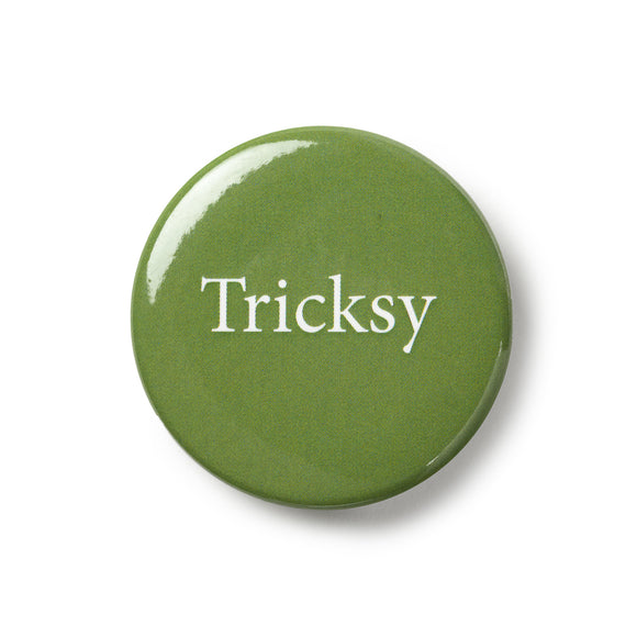 Green button badge with traditional pin fastening. White text says 'Tricksy'.